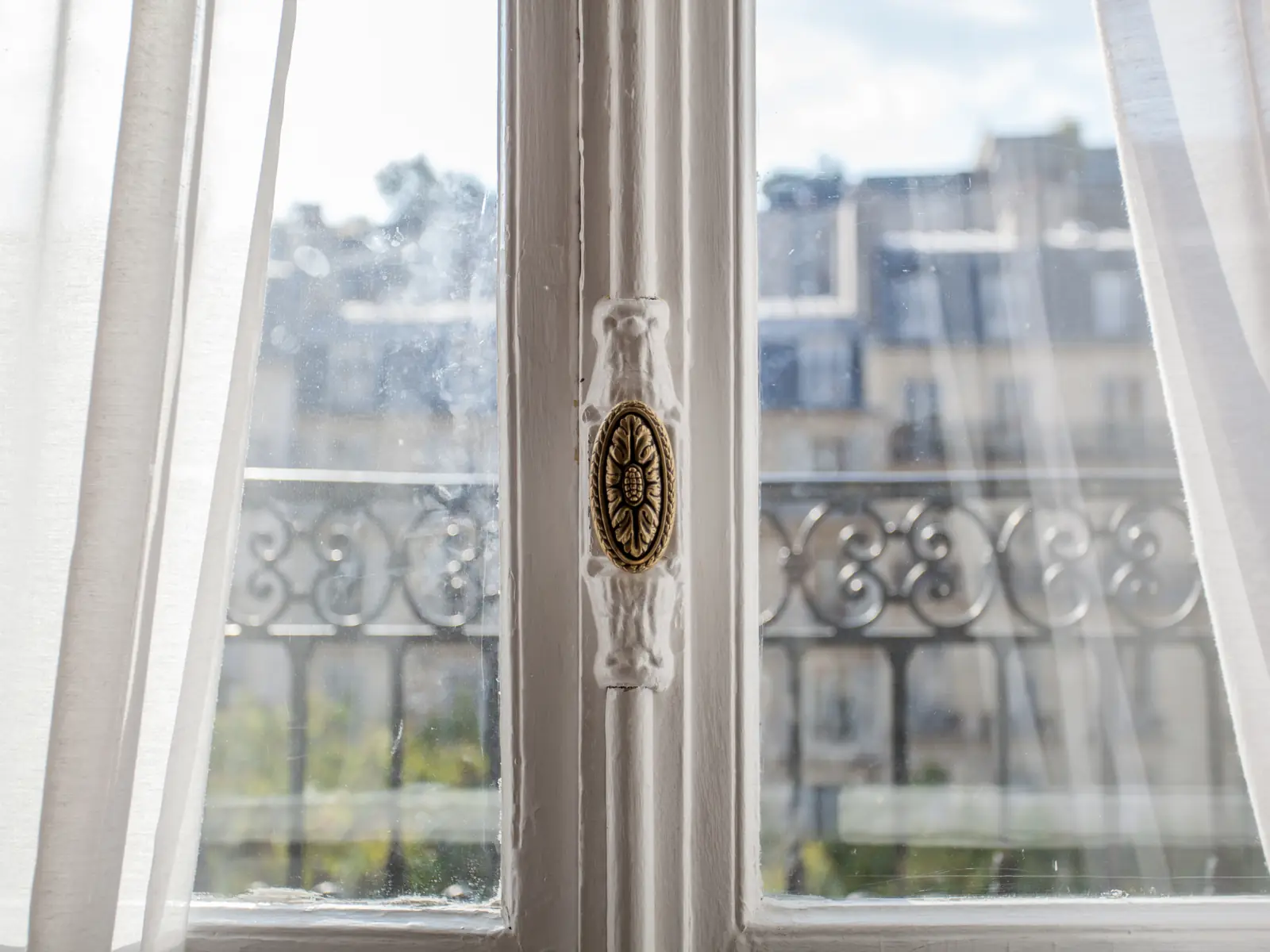 Fenêtre parisienne et ses rideaux ouverts sur les toits