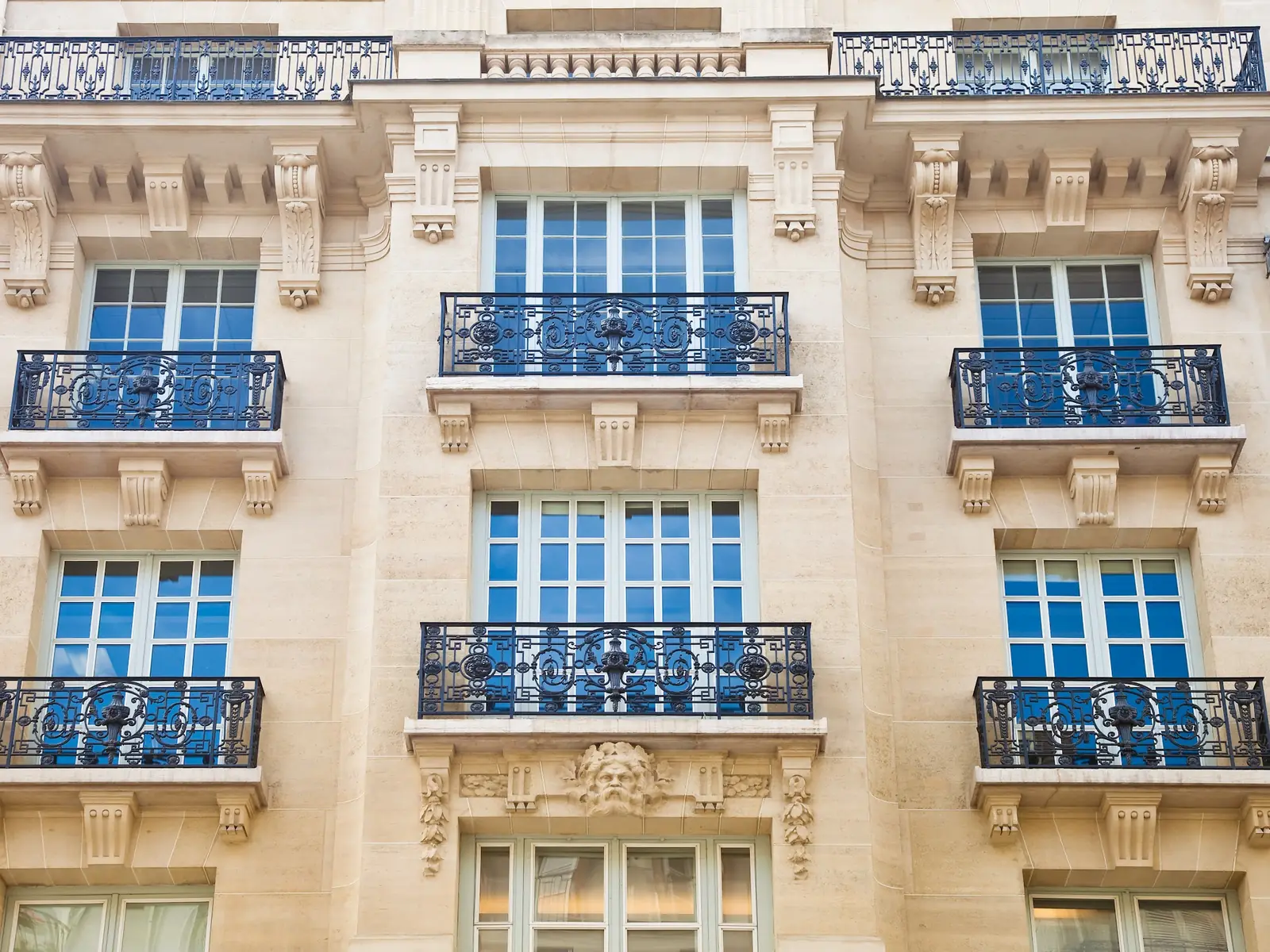 Façade parisienne aux balcons en fer forgé et volets bleus