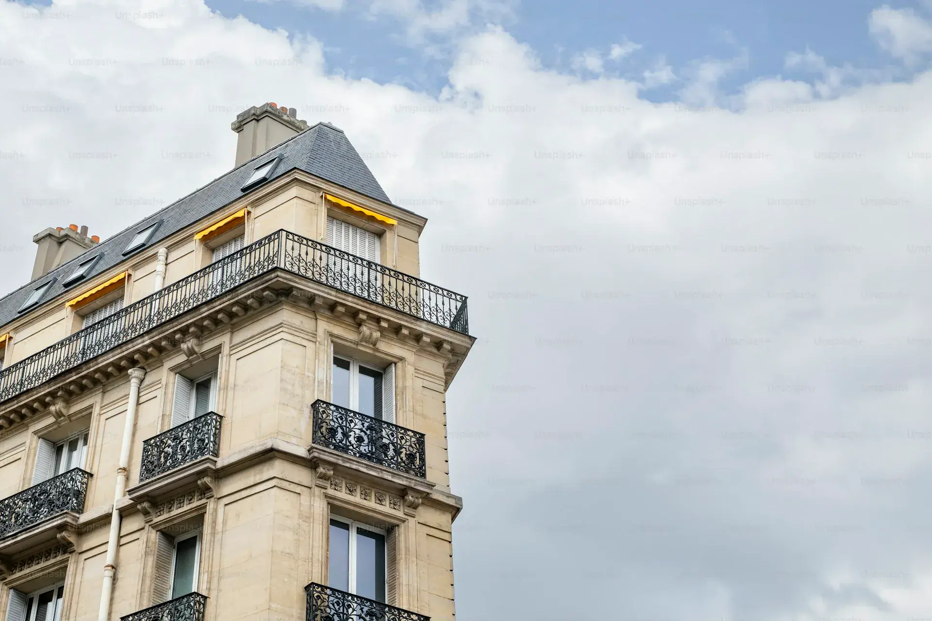 Façade d'un immeuble haussmannien parisien avec balcons en fer forgé et volets ouverts