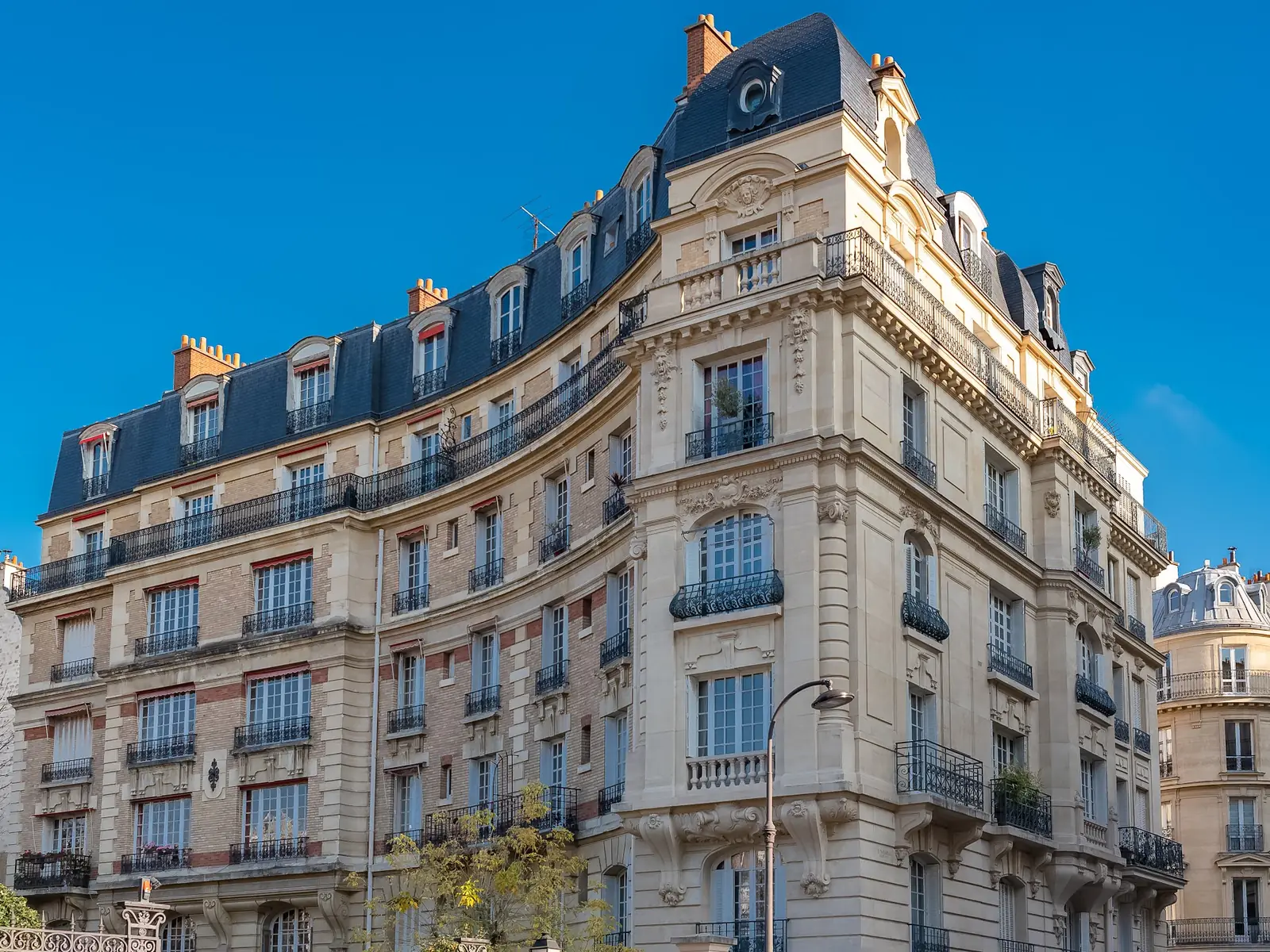 Immeuble haussmannien d'angle à Paris, pierre de taille et balcons en fer forgé