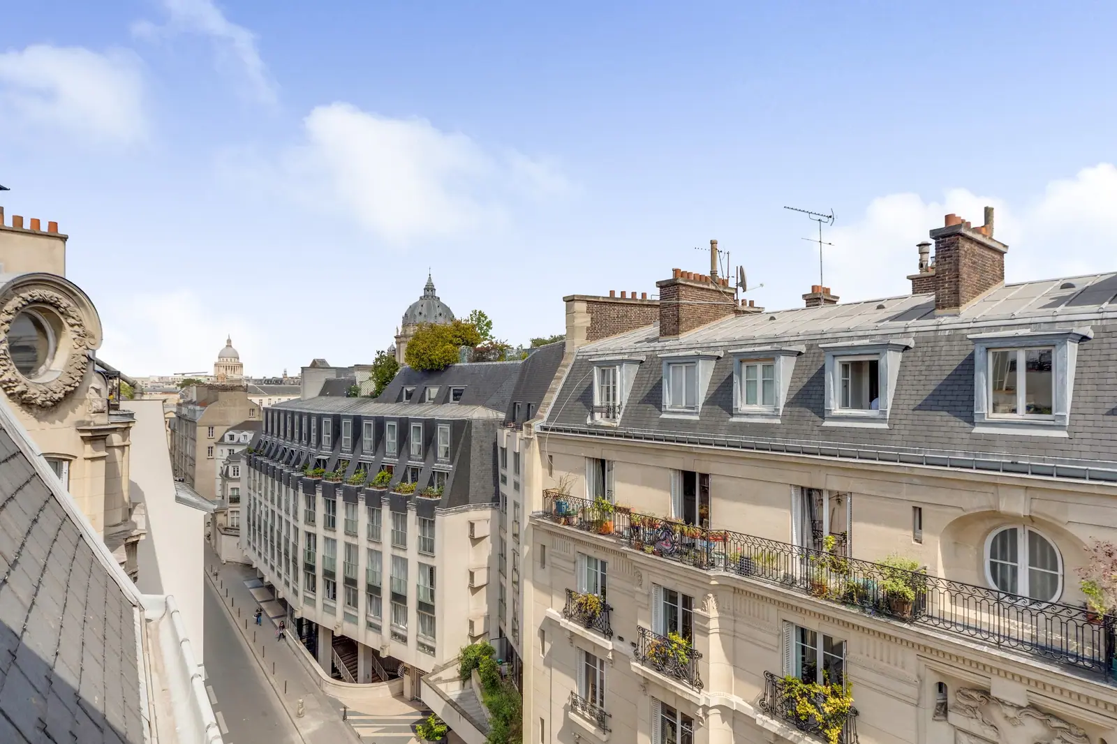 Vue sur les toits en zinc de Paris depuis le balcon d'un appartement haussmannien