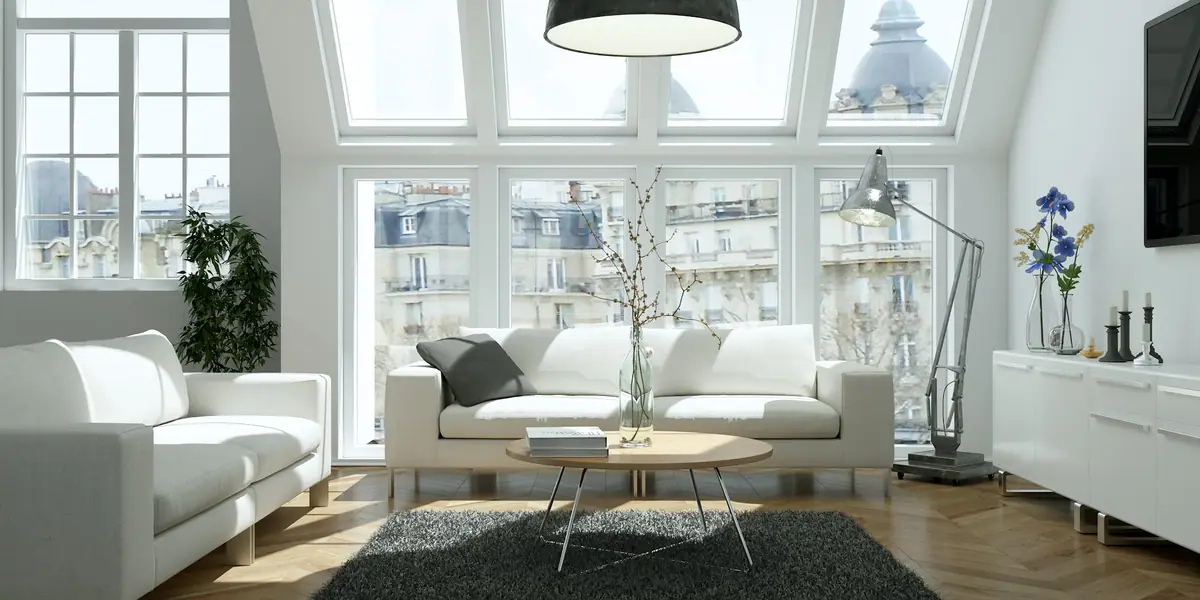 Séjour mansardé lumineux d'un appartement parisien, parquet et poutres apparentes