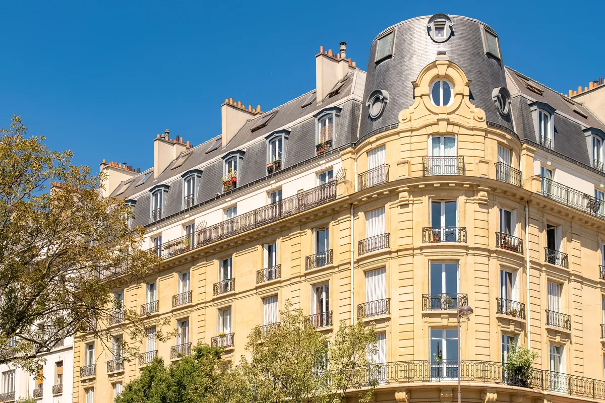 Façade d'un immeuble haussmannien d'angle en pierre de taille, lumière dorée