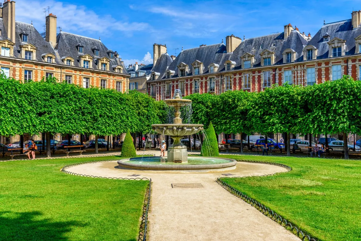 La place des Vosges, sa fontaine et ses pavillons de brique et de pierre, dans le Marais