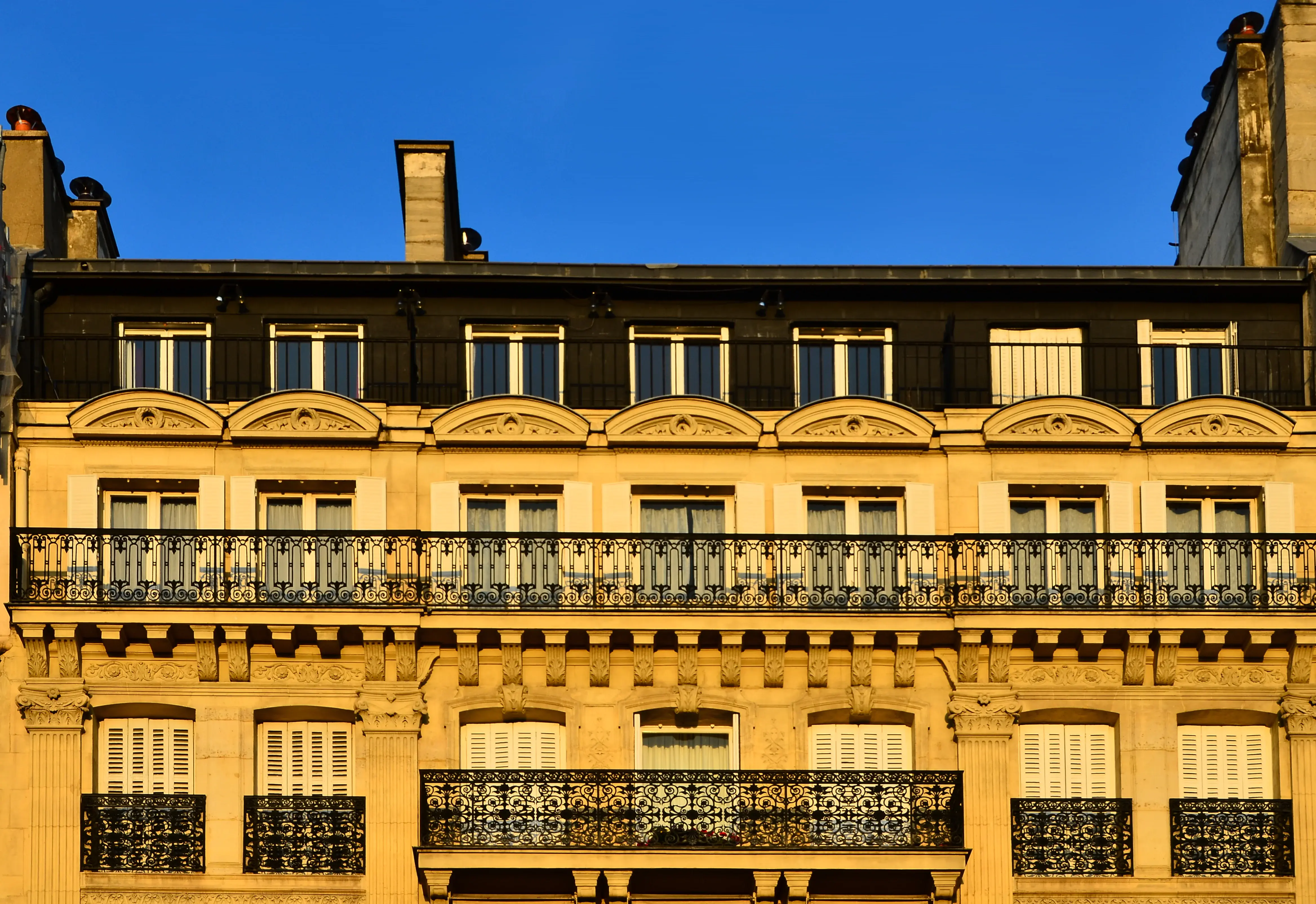 Façade haussmannienne dorée par le soleil couchant à Paris