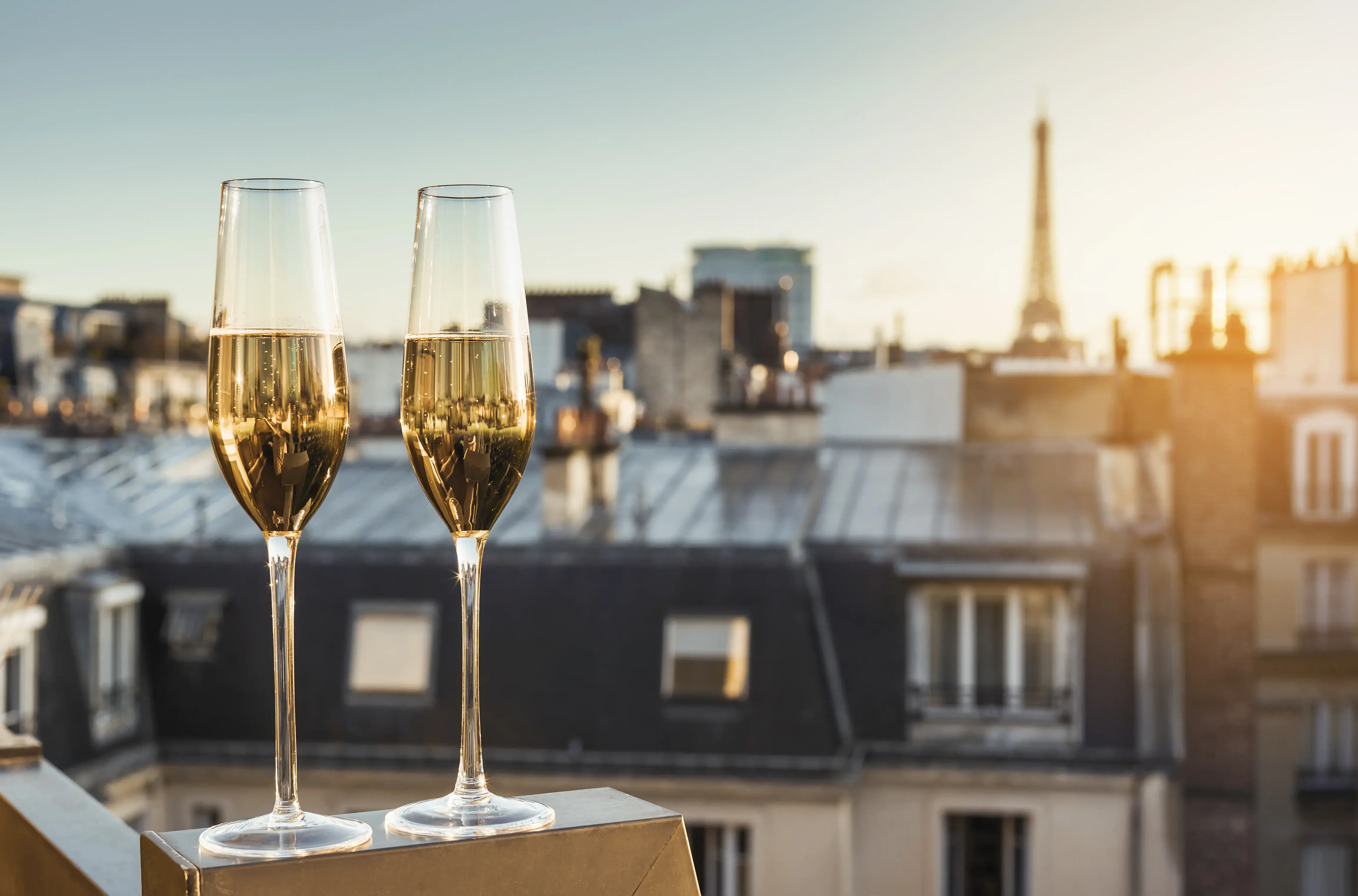 Coupes de champagne devant les toits de Paris au coucher de soleil